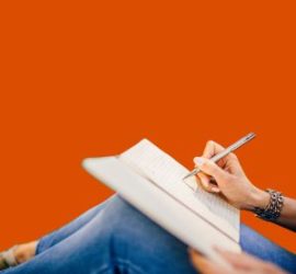Personne qui écrit dans un caret posé sur ces genoux